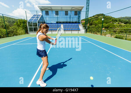 Femmina giocatore di tennis di eseguire un drop shot su una bella corte blu Foto Stock