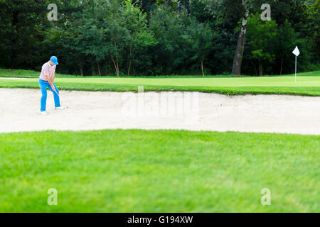 Il Golfer prendendo un bunker shot con la sfera essendo in sabbia Foto Stock