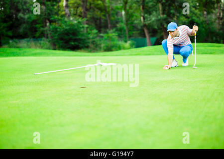 Giocatore di Golf palla di marcatura sul putting green prima del sollevamento della sfera Foto Stock