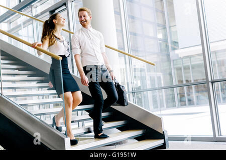 Colleghi di lavoro parlando su scale e flirtare mentre sorridente Foto Stock