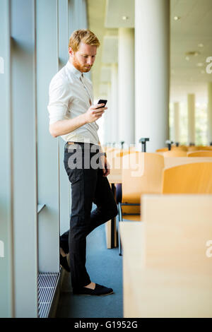 Imprenditore rilassato avente una pausa e guardando il suo telefono Foto Stock