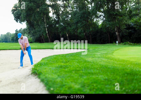 Il Golfer prendendo un bunker shot con la sfera essendo in sabbia Foto Stock