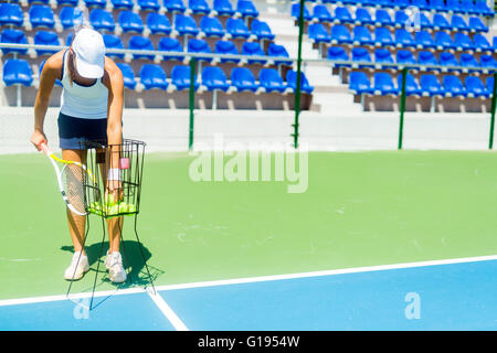 Femmina giocatore di tennis la pratica di servizio con la sfera cestello essendo a portata di mano Foto Stock