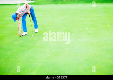 Giocatore di Golf riparazione foro su un verde erba superficie Foto Stock