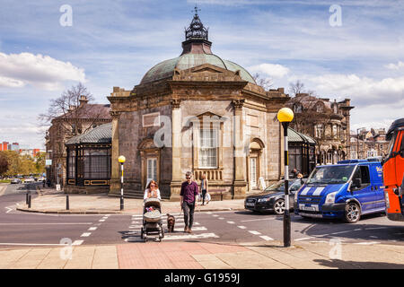 Famiglia giovane con il bambino nel passeggino e cane sul piombo, attraversamento di strada in corrispondenza di un incrocio di zebra al di fuori del Royal Pump Room, Harrogate, Nord Foto Stock
