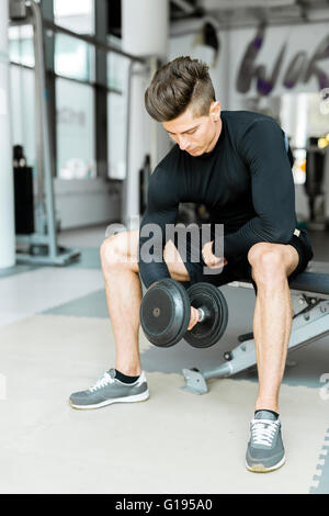 Giovane uomo bello la formazione in un centro fitness Foto Stock
