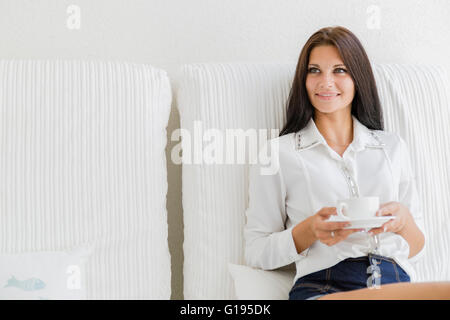 Bella giovane donna felice sorseggiando un tè Foto Stock