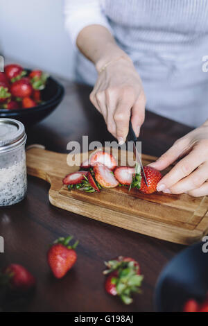 Una donna è per affettare le fragole. Foto Stock
