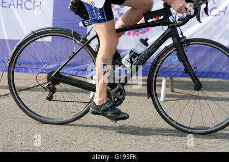 Triatleta lasciando area di transizione in bicicletta a Stratford Triathlon, Warwickshire, Regno Unito Foto Stock