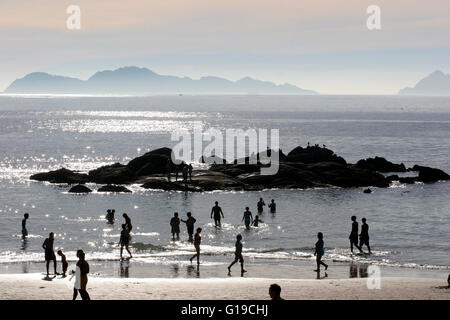 Walkers sul galiziano Playa de Samil spiaggia al tramonto Cies isola in background Spagna Foto Stock