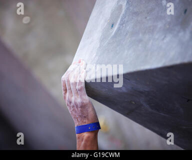 Primo piano della mano d'uomo sulla maniglia sulla artificiale di arrampicata, mano nella messa a fuoco Foto Stock