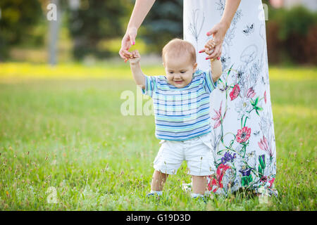 Baby boy passeggiate nel parco con mamma del supporto Foto Stock