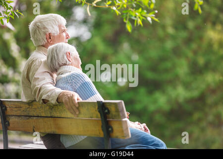 Coppia di anziani in appoggio su una panchina nel parco Foto Stock
