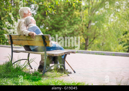 Coppia di anziani in appoggio su una panchina nel parco Foto Stock