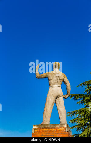 Tozzo muscolare e la statua di ispirazione dal periodo fascista, un caparbiamente uomo alza il braccio sinistro verso il cielo Foto Stock