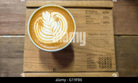 Caffè con foglie di colore bianco latte art sulla tavola di legno Foto Stock