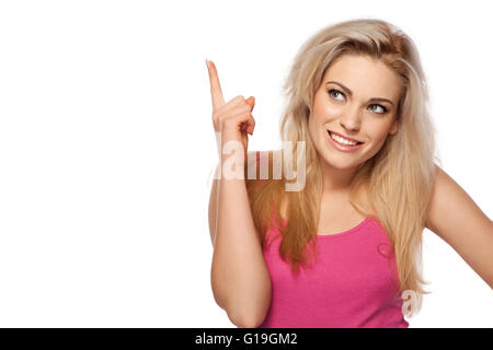 Bella giovane donna puntando il dito sopra la sua testa la nostra attenzione verso copyspace vuoto Foto Stock