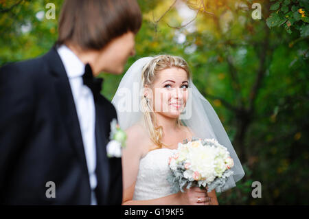 Bella sposa guardando sopra la sua spalla e sorridente Foto Stock