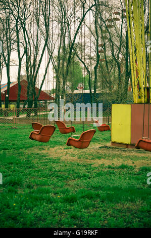 Molla di vuoto il vecchio parco di divertimenti, catena giostra swing attende i visitatori, (filtrato per LoMo effetto) Foto Stock