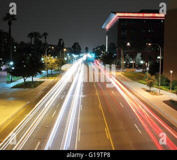 Strada di città di notte nel centro cittadino con percorsi di luce dal traffico in transito Foto Stock