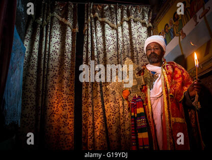 Ortodossa Etiope sacerdote tenendo una croce all'interno di una chiesa rupestre, Amhara Region, Lalibela, Etiopia Foto Stock