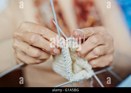 Le mani della donna anziana calza a maglia Foto Stock