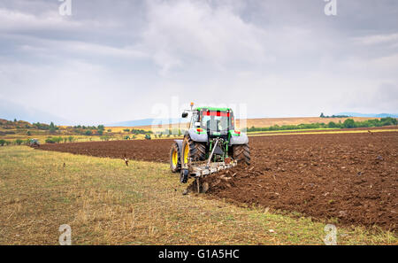 Karlovo, Bulgaria - Agosto 22th, 2015: aratura un campo con John Deere 7230R il trattore. John Deere 8100 è stato fabbricato nel 1995 Foto Stock