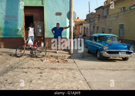 Un vecchio classico anni cinquanta la vettura americana passando un telefono pubblico coda su un angolo di strada in Trinidad, Cuba Foto Stock