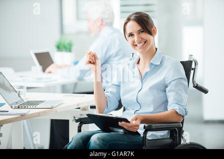 Femmina felice lavoratore di ufficio in carrozzella tenendo un clipboard e sorridente alla fotocamera, persone disabili sostegno al lavoro Foto Stock