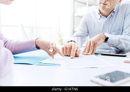 La gente di affari di negoziare un contratto, essi stanno puntando su un documento e discutendo insieme Foto Stock