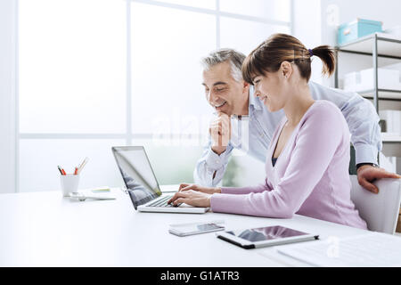 La gente di affari lavorare alla scrivania in ufficio, è una donna con un computer portatile e il suo capo è di guardare lo schermo del computer Foto Stock