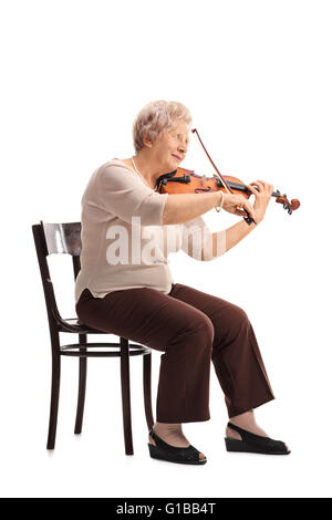 Colpo verticale di una signora anziana giocando un violino seduto su una sedia isolati su sfondo bianco Foto Stock