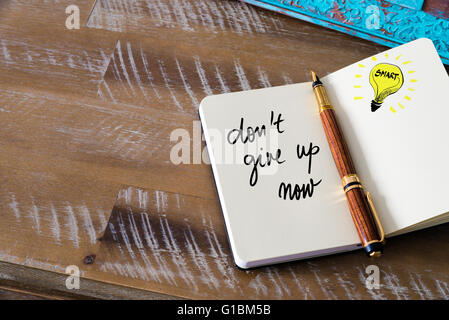 Il testo scritto a mano non arrenderti ora con penna stilografica sul notebook. Concetto di immagine con copia spazio disponibile. Foto Stock