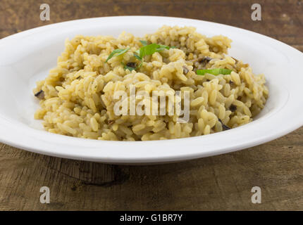 Risotto ai funghi Riso cotto in prossimità fino in piastra bianca su legno Foto Stock