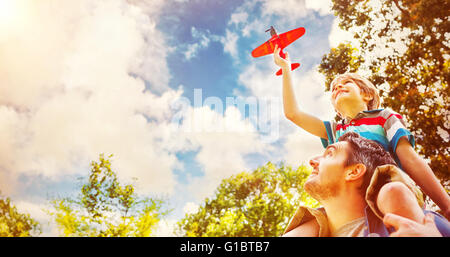 Ragazzo con aeroplano giocattolo seduto sulle spalle dei padri Foto Stock