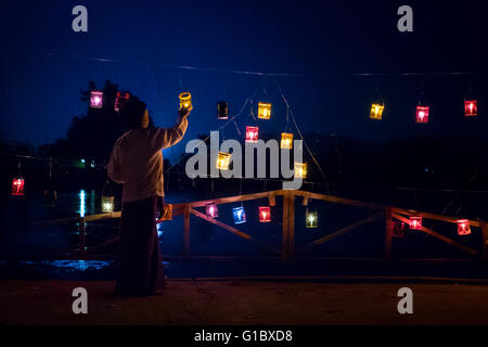 Un giovane ragazzo accendendo candele lungo il fiume in Hsipaw durante il "Festival Thidingyut. Il festival si terrà durante la luna piena alla fine di ottobre e segna il giorno Signore Buddha è disceso dal cielo dopo aver trascorso tre mesi della quaresima buddista. Il Buddha di ritorno è apprezzato in Myanmar con colorate luminarie e persone rilasciando i fuochi d'artificio e lanterne in cielo. Foto Stock