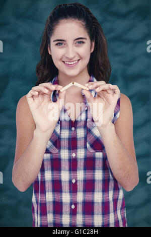 Immagine composita della donna sorridente scattare una sigaretta su sfondo bianco Foto Stock