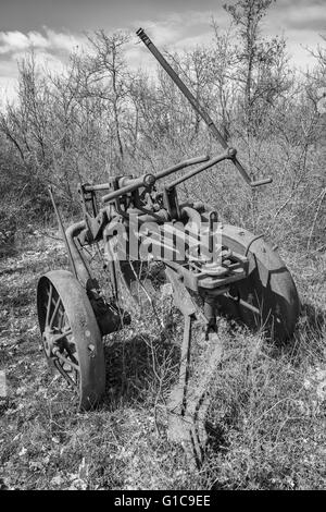 Vecchio di ferro arrugginito aratro abbandonato in un campo incolto. Foto Stock