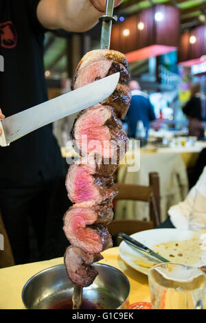 Picanha, tradizionale barbecue brasiliano affettato direttamente al ristorante tavolo. Foto Stock