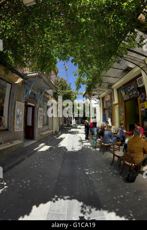 Le persone che si godono le loro bevande in ombra area di una caffetteria locale su P. Kida street. Mirina centro città,Limnos o Lemnos, Grecia Foto Stock