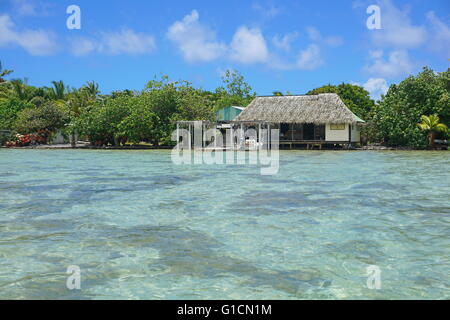 Acque poco profonde della laguna con tipica casa sulla riva di un isolotto, Huahine isola, oceano pacifico, Polinesia Francese Foto Stock