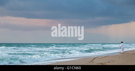Indialantic, Florida - Una donna orologi il oceano Atlantico al mattino presto su un isola barriera. Foto Stock