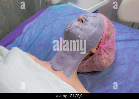 Giovane donna con centro termale viso maschera sul viso Foto Stock