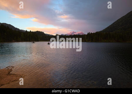 I pescatori sulle barche sul lago Hintersee in una piovosa, colorato tramonto, Berchtesgaden, Baviera, Germania Foto Stock