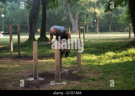 Atleta lavorando fuori mano Stand su barre parallele in una palestra a cielo aperto - strada facendo esercizi di allenamento Foto Stock