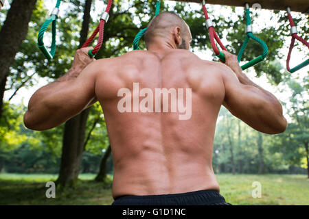 In primo piano costruito muscolare giovane atleta che lavora fuori in una palestra a cielo aperto - Facendo Chin-Ups Foto Stock