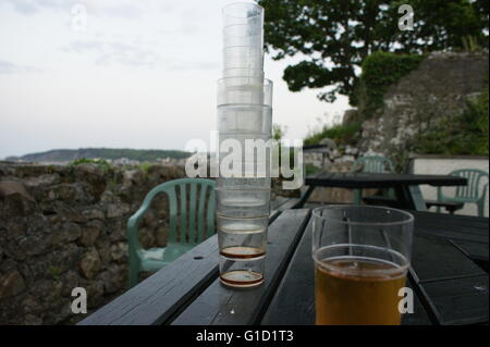 La pinta di birra e bicchieri vuoti la pinzatura di un massimo sul tavolo, outdoor presso un cucciolo, nei pressi della spiaggia in Galles Foto Stock