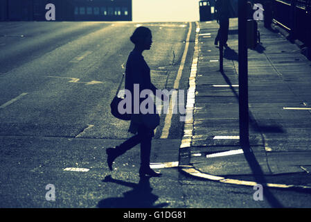 Silhouette di donna giovane signorile sulla strada di Glasgow con road contre-jour retro-illuminato in Glasgow, Scotland, Regno Unito. Foto Stock