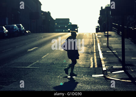 Silhouette di donna giovane sulla strada di Glasgow con road contre-jour retroilluminato in Glasgow, Scotland, Regno Unito. Foto Stock