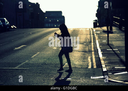 Silhouette di donna giovane ragazza sulla strada di Glasgow con road contre-jour retroilluminato in Glasgow, Scotland, Regno Unito. Foto Stock